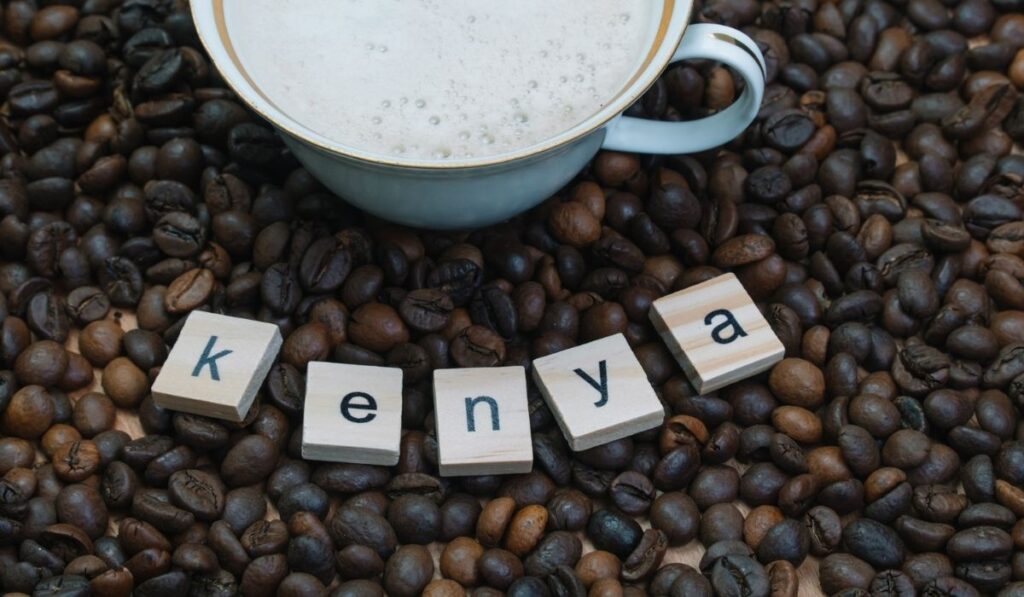 Porcelain and gilded cup of coffee on a background of coffee beans with the inscription Kenya