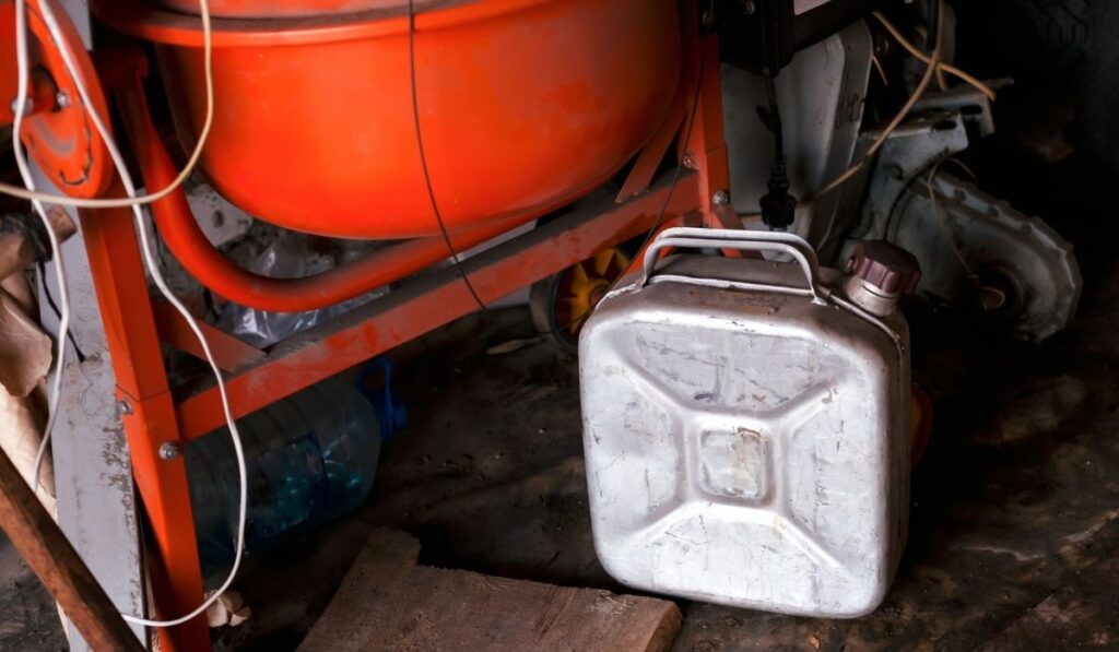 A silver gas can in dark dusty garage