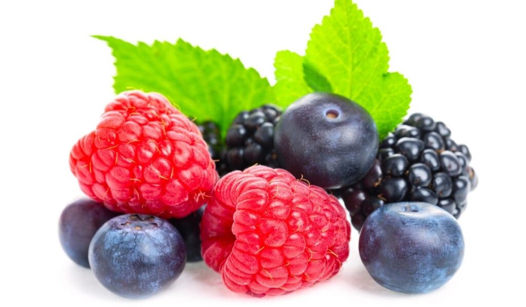 Macro shot of fresh raspberries, blueberries and blackberries with leaf isolated on white background