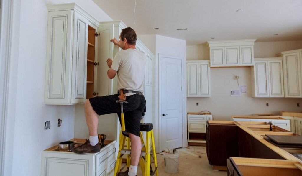 Worker installs doors to kitchen cabinet