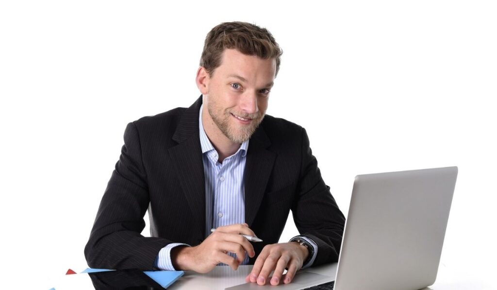 Young attractive businessman working happy at computer desk satisfied and smiling relaxed 