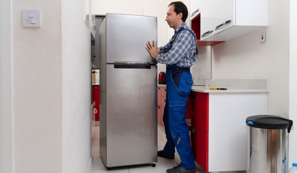 Mover Placing Refrigerator In Kitchen