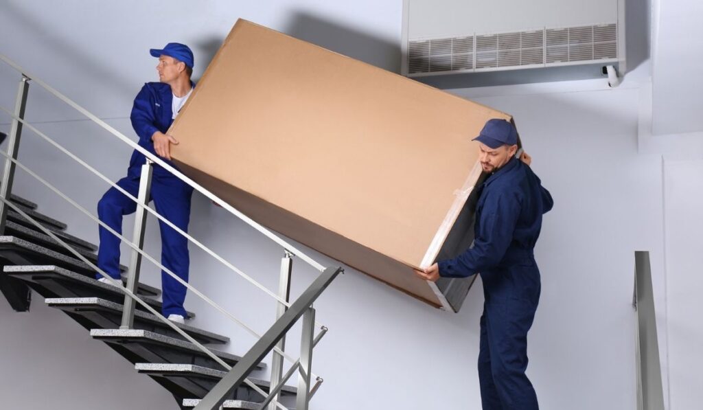 Professional workers carrying refrigerator on stairs