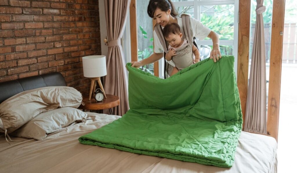 Asian mom carries the baby cleaning and arranges blanket