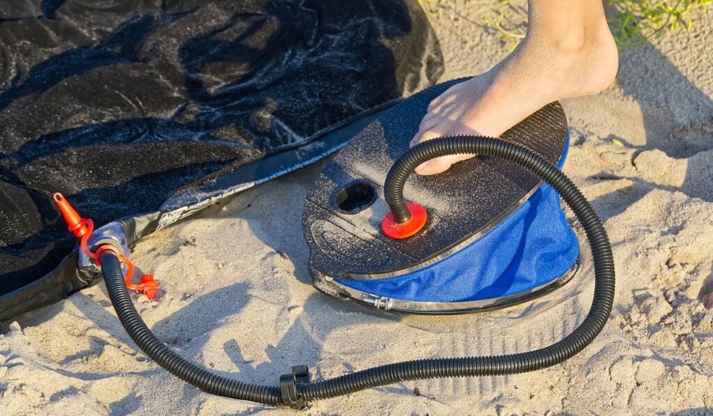 A Man with air foot pump pumps an inflatable mattress