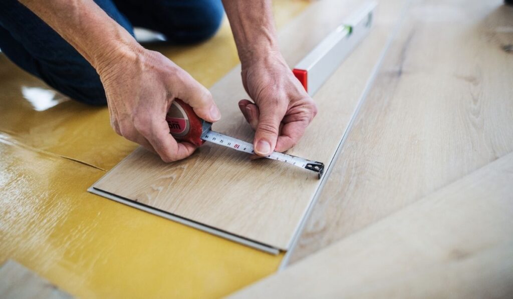 A midsection of senior man laying vinyl flooring 