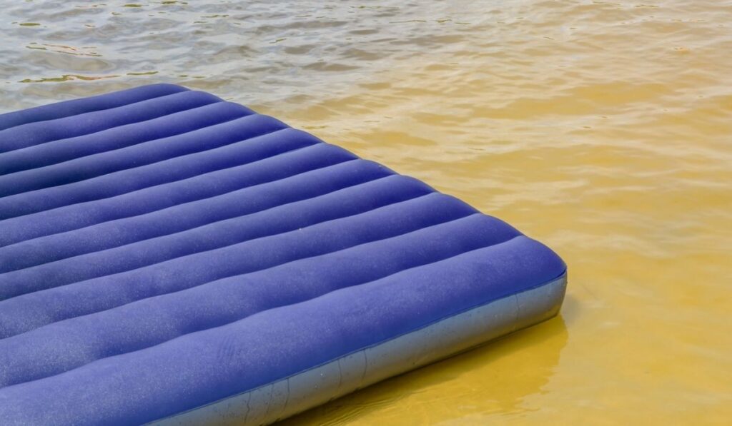 Blue inflatable mattress on the summer shore of the river or lake 