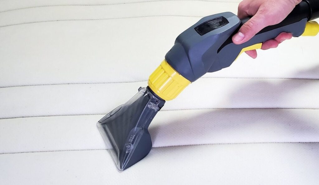 Man`s hand cleans a modern white mattress with a professional cleaning agent 