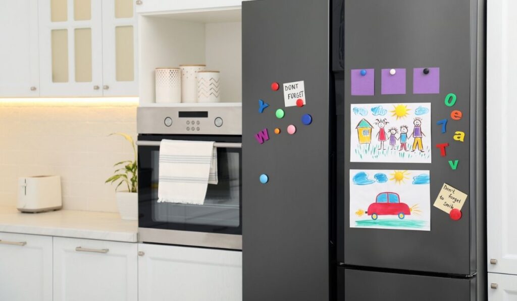Modern refrigerator with child`s drawings
