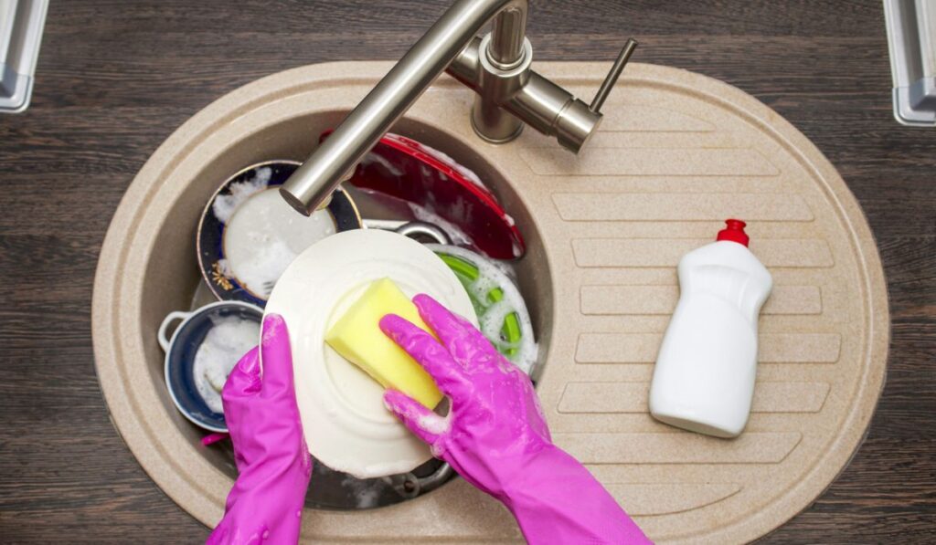 Close up hands of woman washing dishes in kitchen 