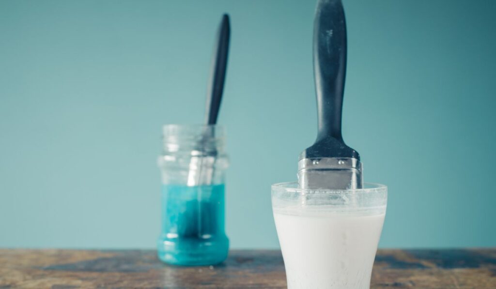 Two paintbrushes soaking in jars