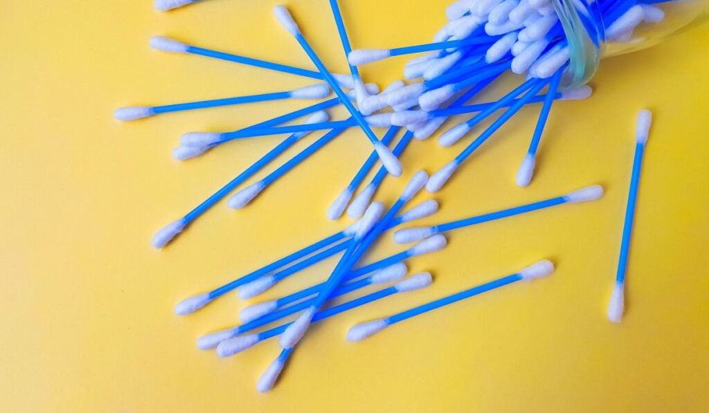 Cotton sticks ear blue plastic on a yellow background 
