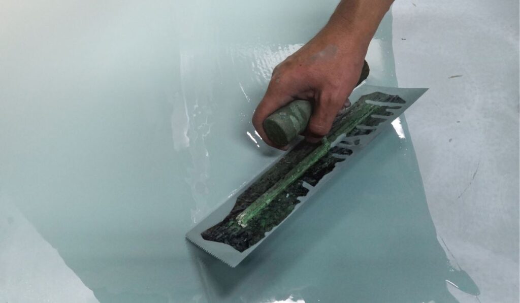 Construction workers are painting the floor using the method self-leveling epoxy