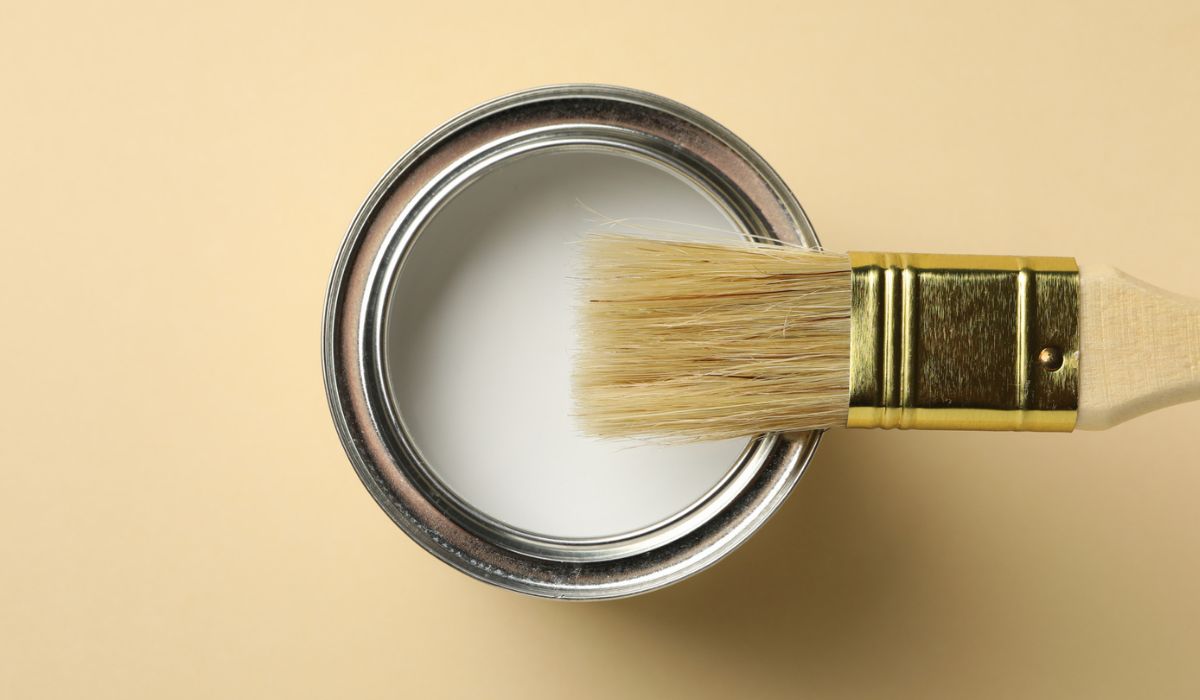 Paint can and brush on beige background