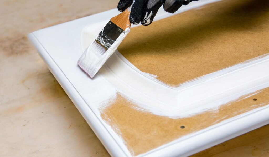 Repainting kitchen cabinet doors with white chalk paint indoors at home