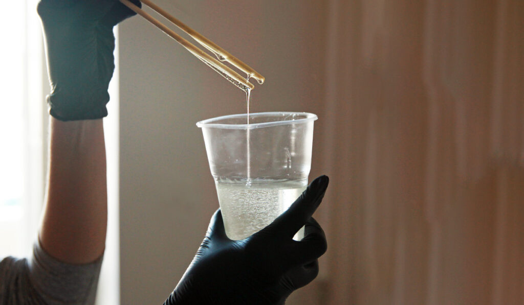 close up of hands holding a mixed cup of epoxy